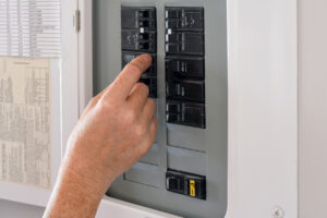 A hand flipping on circuit breaker panel switches.